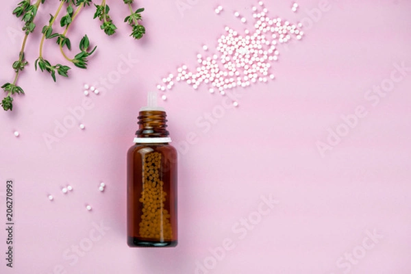 Fototapeta Flat lay of brown glass bottle with plenty of white homeopathic pills on pink surface. Homeopathic lactose sugar balls in glass bottles,medicine. Bottle with white sugar pills