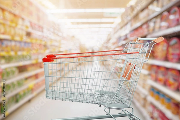 Fototapeta Supermarket aisle with empty shopping cart at grocery store retail business concept