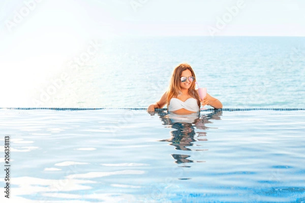 Fototapeta Summer Vacation. Woman in bikini on the inflatable donut mattress in the SPA swimming pool.