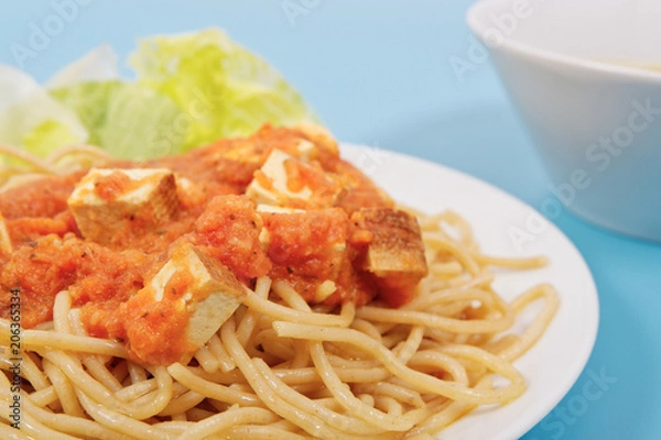 Fototapeta Bolognese spaghetti with tofu on a blue