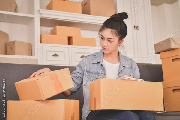 Obraz Sme business concept. Young Asian people are packing their packages.Delivery business  Small and Medium Enterprise (SMEs). Young man is working in the house.Young Owner Start up for Business Online.