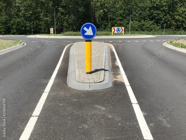 Obraz Yellow Dutch traffic column with driving direction in front of a roundabout