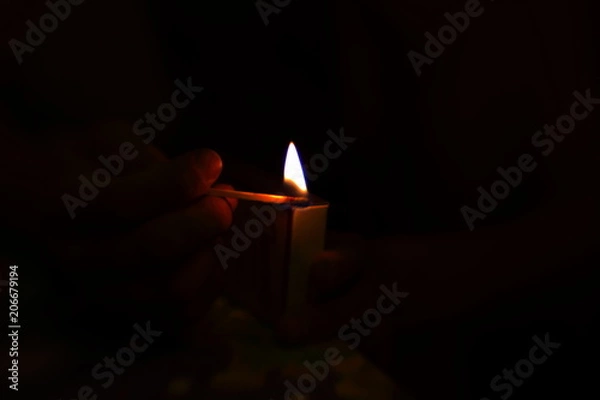 Obraz lighting a candle in the dark