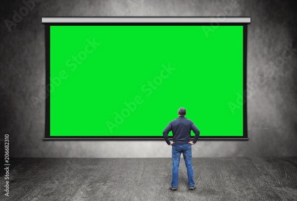 Fototapeta Man stands in front of big empty green screen