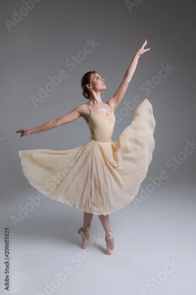Fototapeta The blessing of a dancer! Full length picture of the young graceful charming smiling girl dancing in the modern ballet studio.