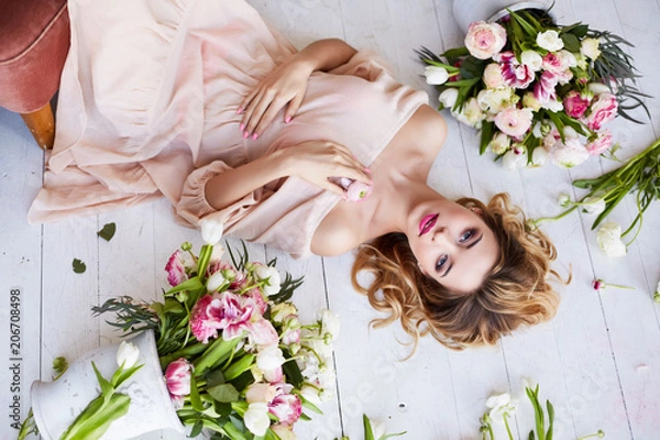 Fototapeta Beautiful young woman with make-up and curls. The girl's face is in flowers.