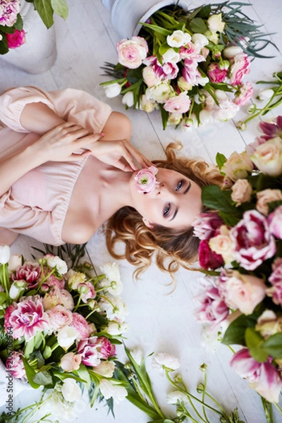 Fototapeta Beautiful young woman with make-up and curls. The girl's face is in flowers.