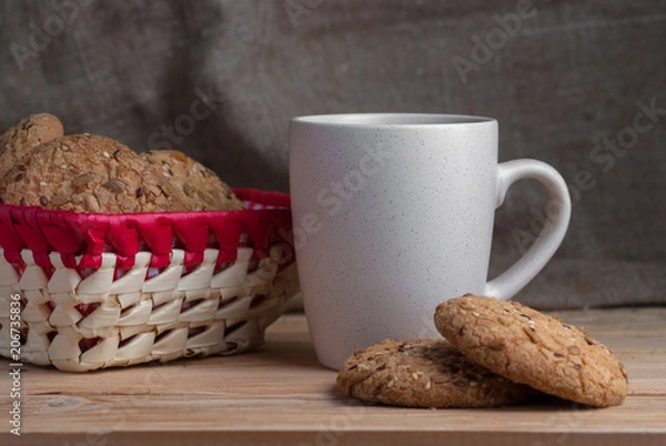 Fototapeta delicious oatmeal cookies with splash of sunflower seeds, sesame seeds on wooden table laid out in row on brown background with cup of tea