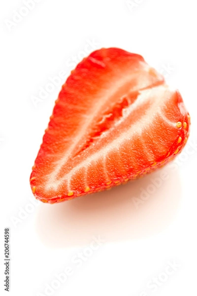 Fototapeta Halve of a strawberry on a reflective white background.