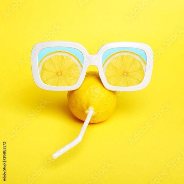 Obraz Minimal lemon in sunglasses with straw on yellow.