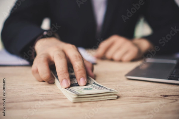 Fototapeta Ręce z bliska: człowiek oferujący partię stu dolarowych. Ręka przekazująca pieniądze - dolary amerykańskie (lub USD). Pojęcie korupcji.