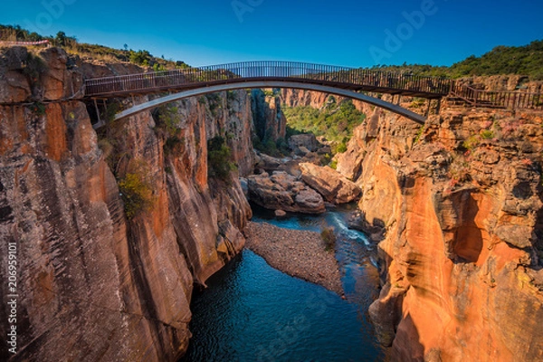 Fototapeta A wide shot of the river gorge and a high bridge at Bourke’s Luck Potholes in Mpumalanga, South Africa; a geological formation carved out by the movement of water