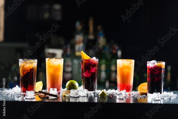 Fototapeta Multi-colored alcoholic cocktails with citrus in glasses of different shapes on the bar.