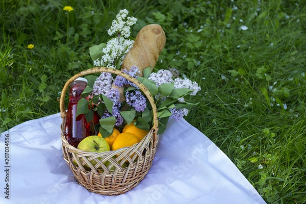 Fototapeta Basket with fruits for a picnic. Picnic in the park on the grass