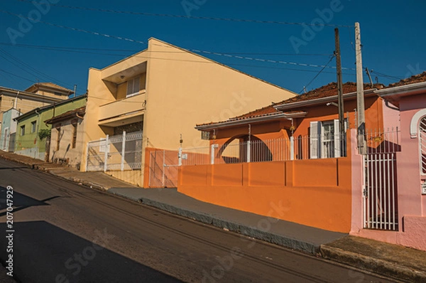 Fototapeta Working-class colored houses and fences in an empty street on a sunny day at São Manuel. A cute little town in the countryside of São Paulo State. Southeast Brazil.