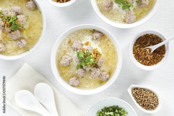 Fototapeta Rice porridge with pork chops and seasoning in white bowls on top view white table, Chinese food.