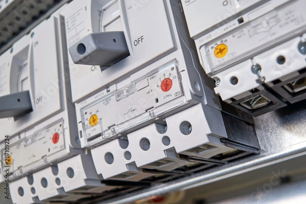 Obraz Three large, modern, powerful circuit breakers in the electrical Cabinet. Reliable protection and distribution of electrical energy in production, industry. Power supply of buildings and facilities.