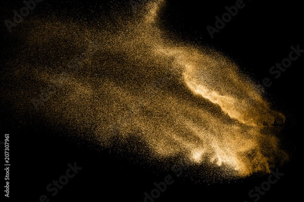 Fototapeta Golden sand explosion isolated on black background. Abstract sand cloud. Golden colored sand splash against dark background. Yellow sand fly wave in the air.