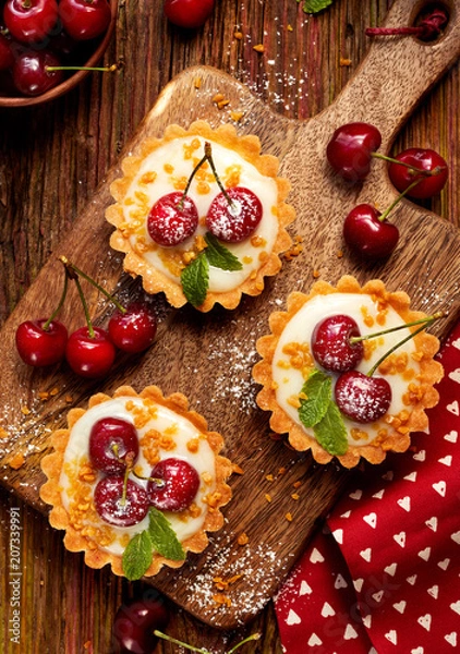 Fototapeta Mini Tarts with fresh cherries and vanilla custard and caramel, delicious dessert on a wooden table, top view