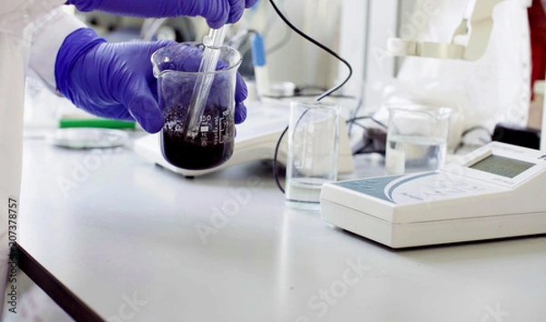 Fototapeta Close up hands of a scientist in the laboratory measuring pH of the sample suspension by electronic pH meter