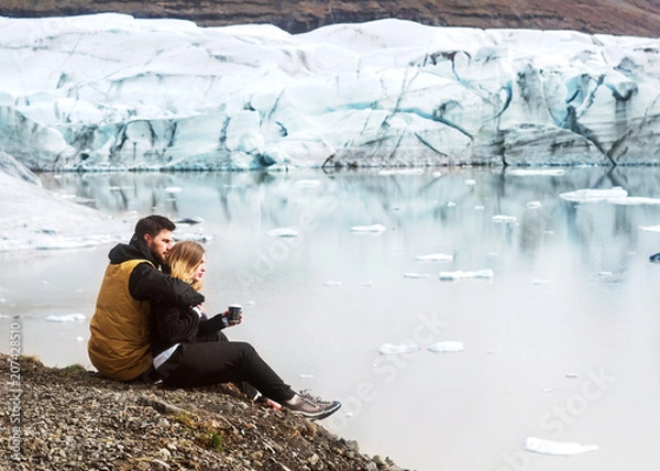 Fototapeta two tourists are sitting near the glacier iceberg in Iceland