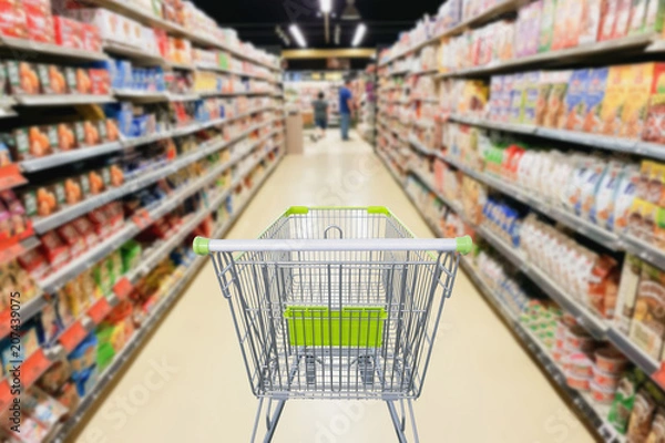 Fototapeta Supermarket aisle with empty shopping cart business concept