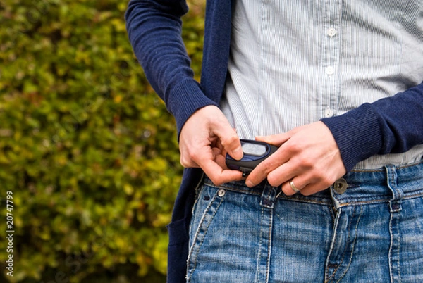 Fototapeta Kobieta sprawdza swój krokomierz podczas spaceru na świeżym powietrzu