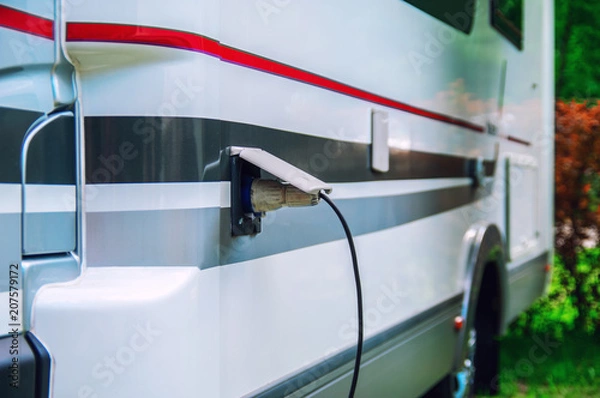 Fototapeta Motorhome stillife. Concept of power supply of the camper. Plug of the electric wire is inserted into the socket of the rv trailer