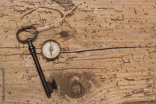 Obraz Old key and compass on a wooden background