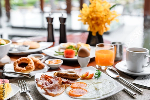 Fototapeta Setting of breakfast includes coffee, fresh orange juice, eggs on table in hotel restaurant