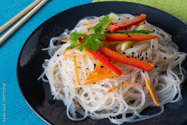 Obraz cellophane noodles on a plate on a wooden table with vegetable sauce and dressing