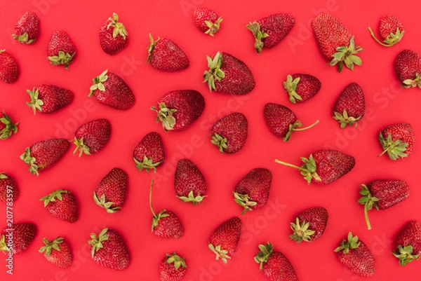 Obraz top view of raw strawberries isolated on red background