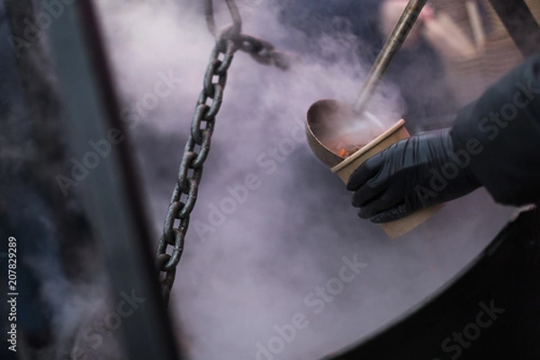 Fototapeta A person pouring some soup in a cup.