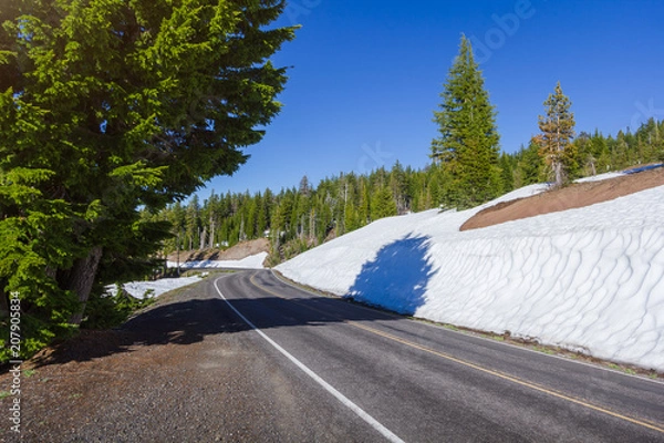 Fototapeta A scenic highway (Rim Drive) in Crater Lake National Park  with snow wall melting along the road in a summer season, Oregon, USA