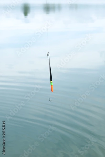 Fototapeta Fishing rod, fishing pole with a cork or float on the line on the lake background