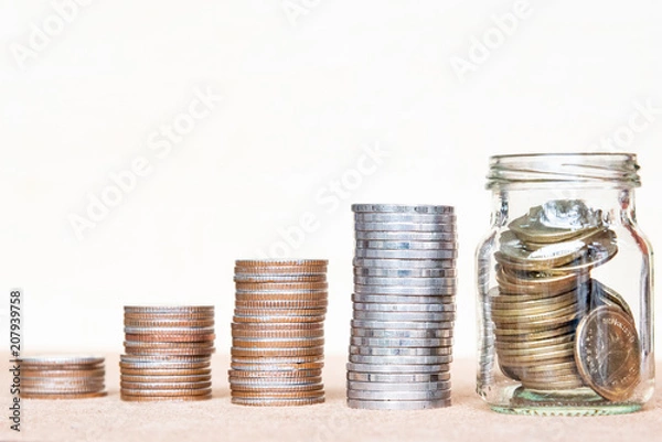 Obraz Glass of coin and four pole range of coins on vintage blurred background - Saving money concept.