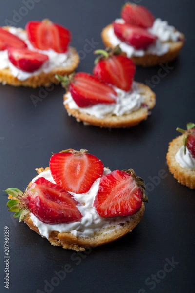 Fototapeta  Fluffy buttermilk biscuits shortcake with red ripe strawberries and fresh whipped cream on a black background