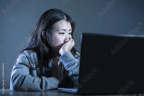Fototapeta pretty sad Asian Korean student woman looking depressed and worried studying with laptop computer in stress for exam feeling bored and frustrated