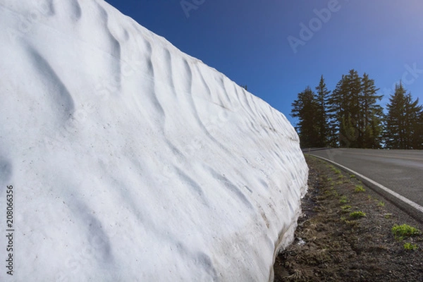Fototapeta July 2017 - Snow wall melting along the road (Rim Drive - Volcanic Legacy Scenic Byway) with sunlight in a summer season, Crater Lake, Oregon, USA