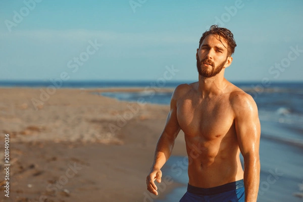 Fototapeta Handsome young man having fun on the beach by the sea