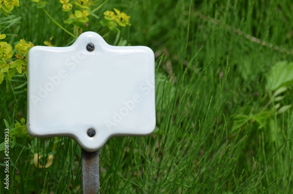 Fototapeta White ceramic sign on grass background with space for text