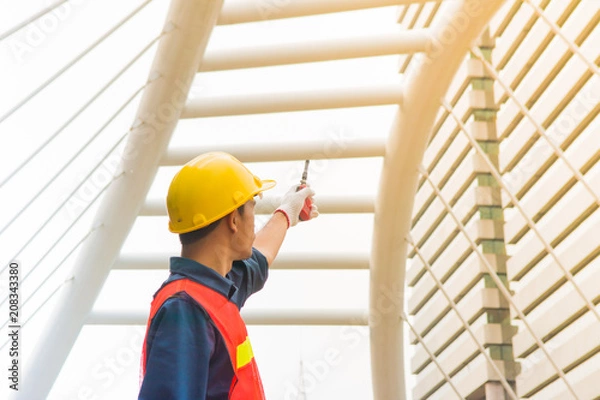 Fototapeta Worker is pointing his hand that holding old red walkie talkie during work out of office