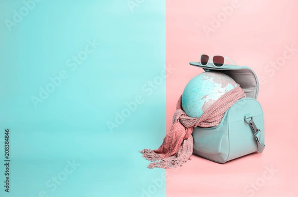 Obraz Travelling globe going on vacation in travel bag with sunglasses and scarf on soft pink and light mint pastel colored background, Copy space, Trendy vanilla colors