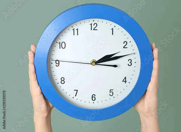 Fototapeta Woman holding clock on color background. Time management concept