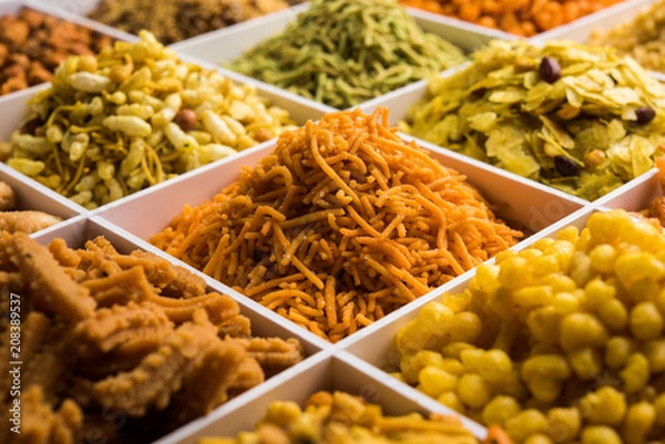 Obraz Indian Tea-time snacks like sev, chivda, farsan, mixture, boondi, bakarwadi etc served in white wooden box with cells. selective focus