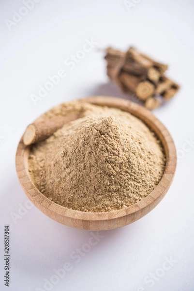 Fototapeta Ayurvedic Mulethi or Liquorice root stick or jeshthamadh powder served in a bowl over moody background