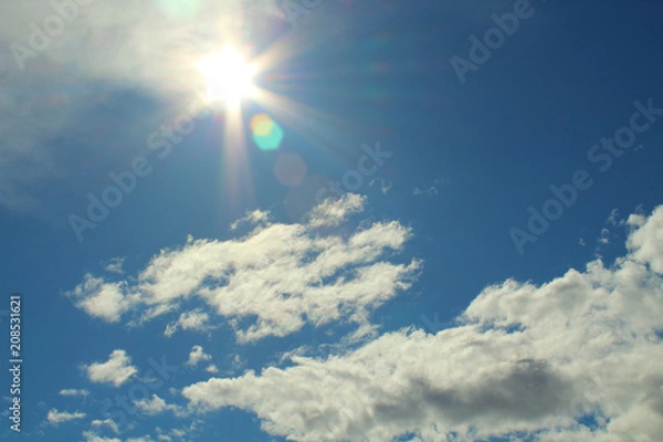Obraz Beautiful natural glow of the sun. Beautiful blue sky and white fluffy clouds. Background. Landscape. 