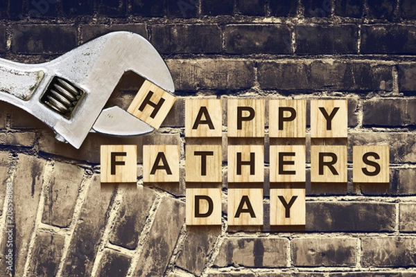 Obraz Happy Fathers Day inscription on wooden cubes with working tools on an old vintage brick wall. Happy Father's Day Concept. Greetings and gifts.