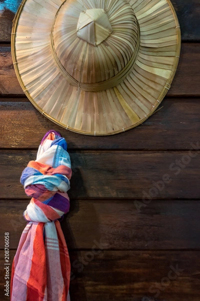 Fototapeta Weave hat and loincloth Thai style with the old wooden table background.