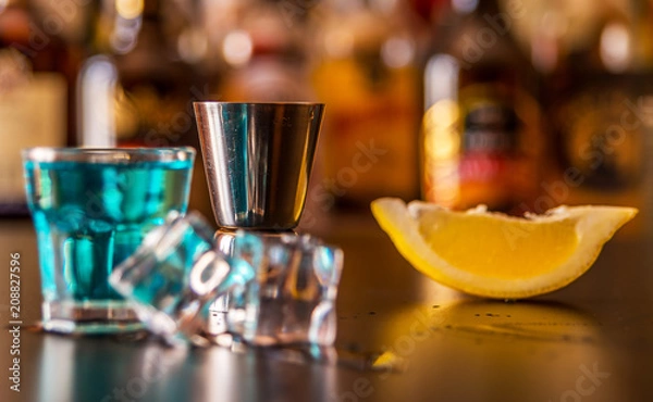 Fototapeta Popular blue drink shot kamikaze on the background of the bar with bottles, a refreshing drink